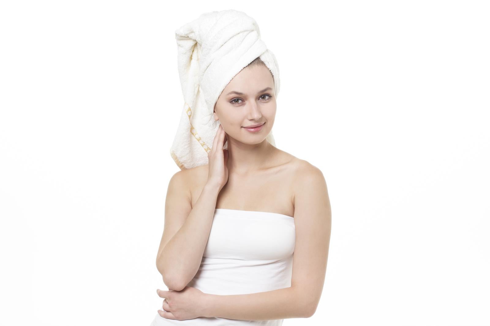 Woman after bathing with white towel wrapped around her head, hand on her cheek