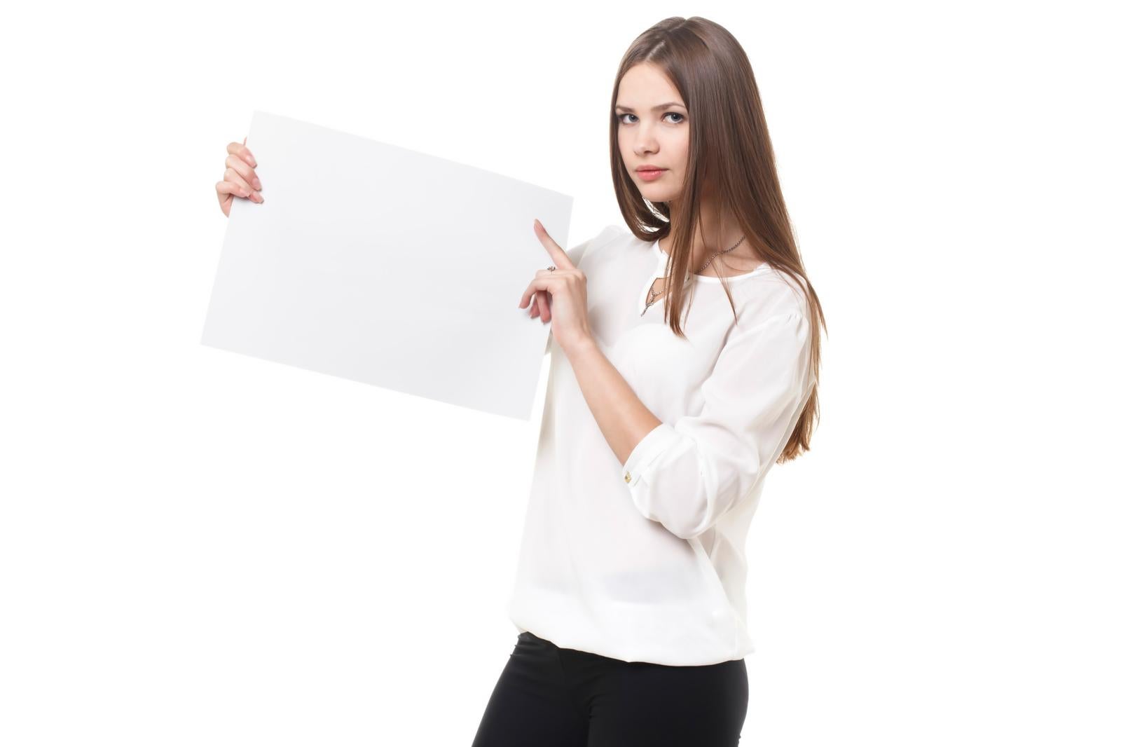 白いパネルを両手で持ちながら指差しポーズで注目を促す白い服の女性［モデル：モデルファクトリー］