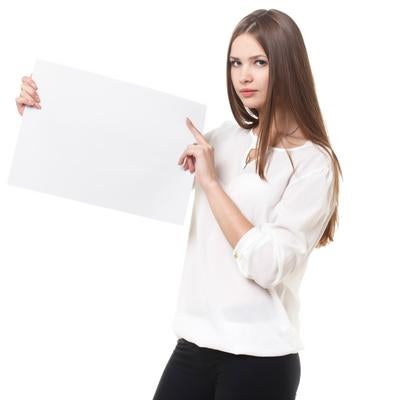 白いパネルを持って指差しポーズをする女性の写真