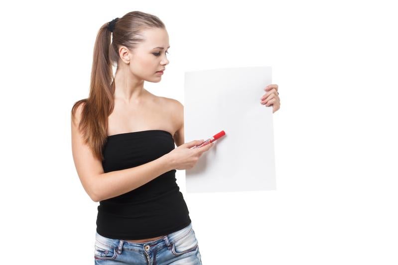 黒いベアトップ姿で白いパネルに文字を書く女性の写真