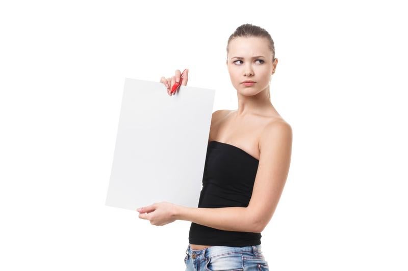 A woman holding a white paper wearing a black halter top and jeans.