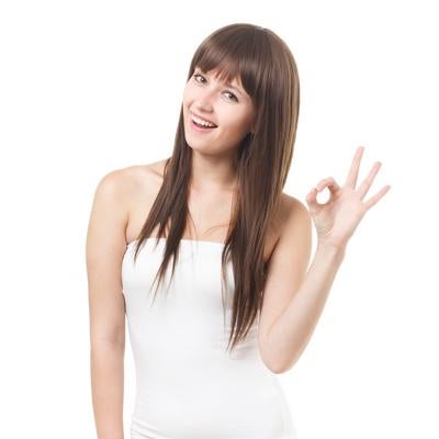 白いベアトップを着て笑顔でOKサインをする長髪の女性の写真