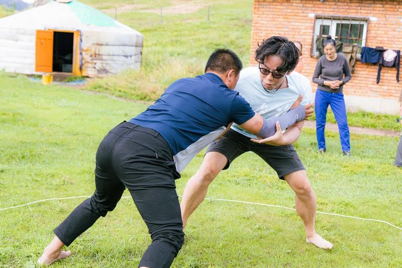 元モンゴル相撲の選手と対戦するもーりーさんの写真