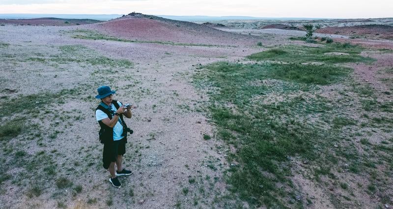 サインシャンドの草原と砂漠の間でドローンを操縦するトラベラーの男性の写真