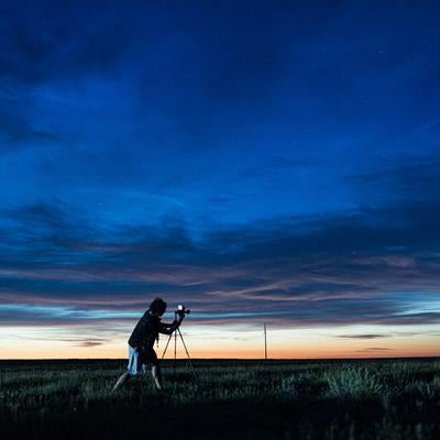 夜明け前の草原を撮影するカメラマンの写真