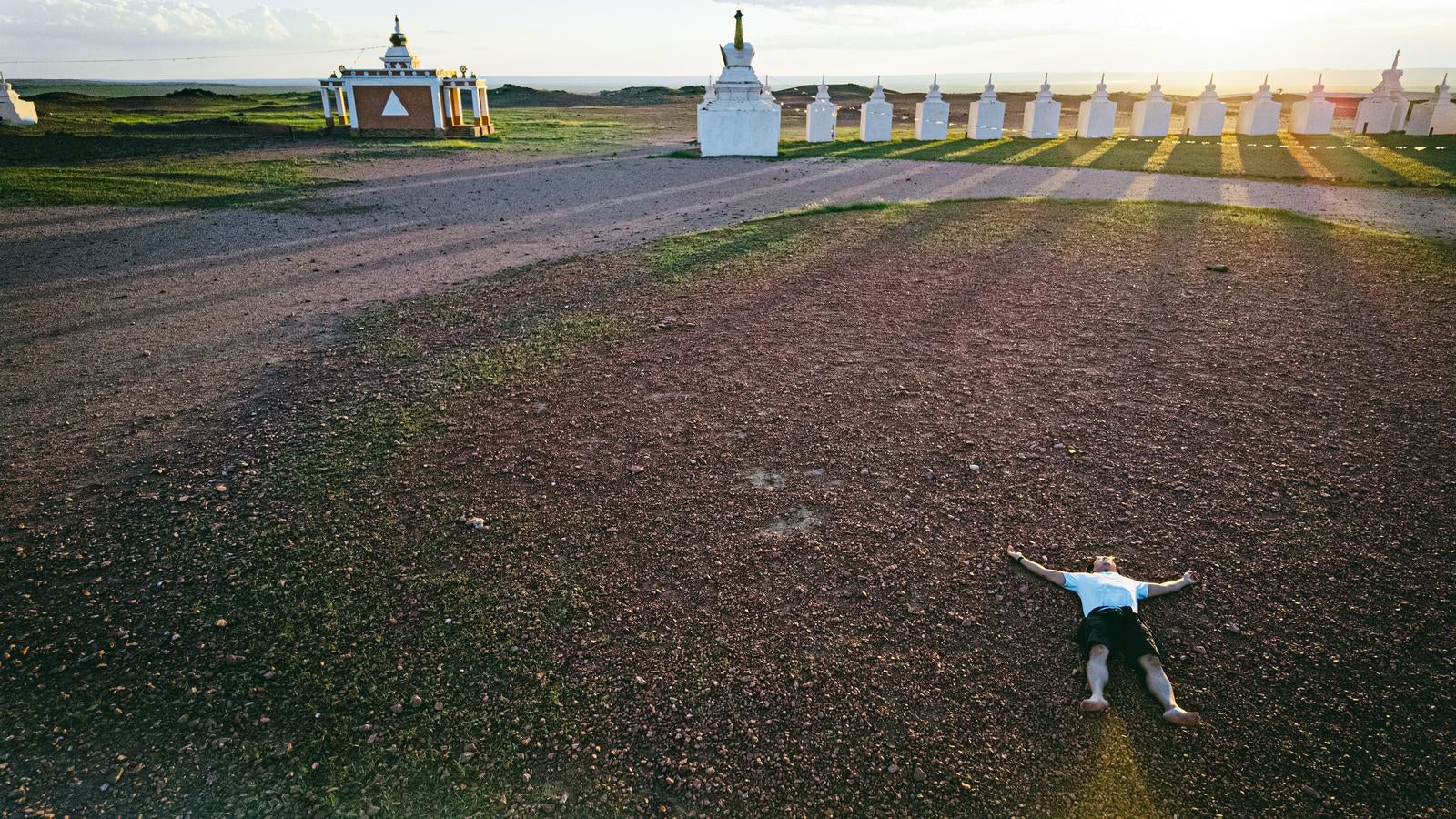 「赤い土に寝そべって大地のエネルギーを吸収する旅行系YouTuber」の写真［モデル：もーりー］