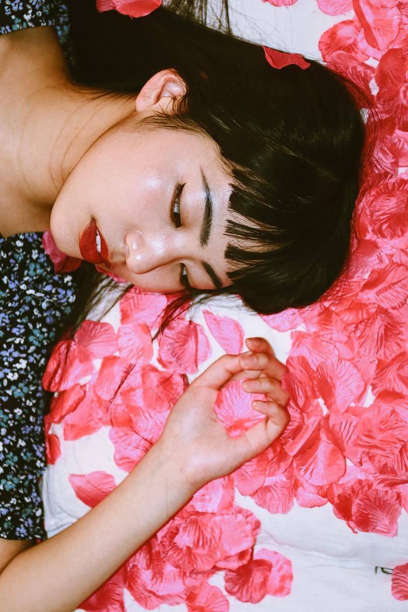 「花びらの中で寝転ぶ女性のポートレート」の写真［モデル：なんこ］