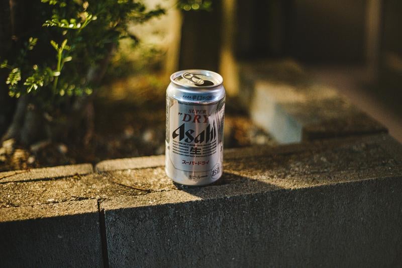 ブロック塀の上に置かれたビールの缶の写真