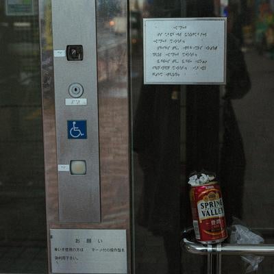 エレベーター前の手摺に置き去りにされた空き缶の写真