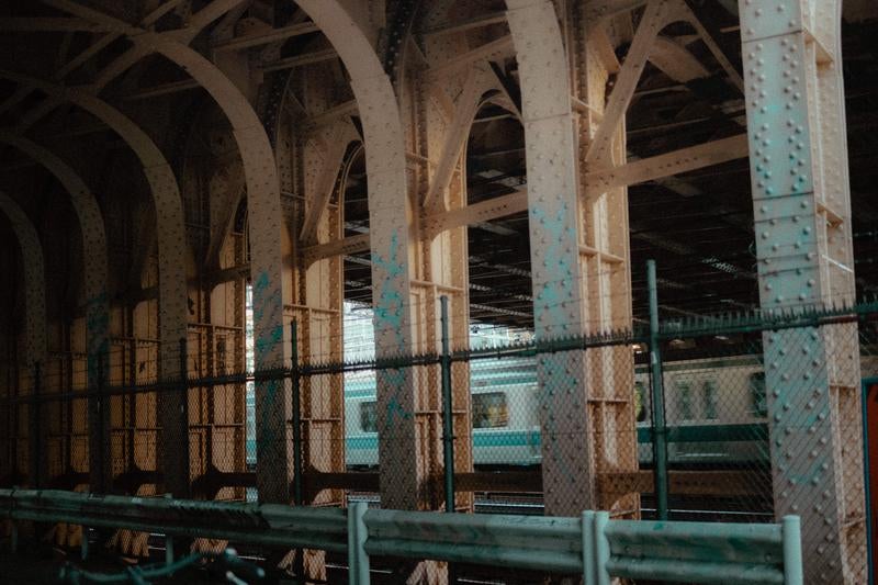 無骨な鉄骨と通り過ぎる電車の写真