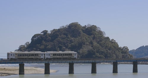 虚空蔵島をバックに走る観光列車「海幸山幸」の写真