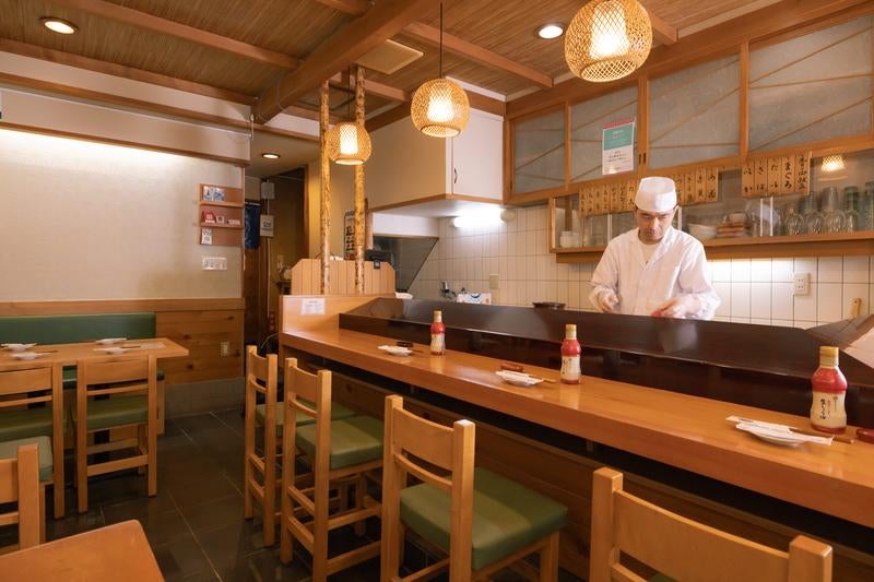 カウンター内で仕込み中の寿司職人の写真