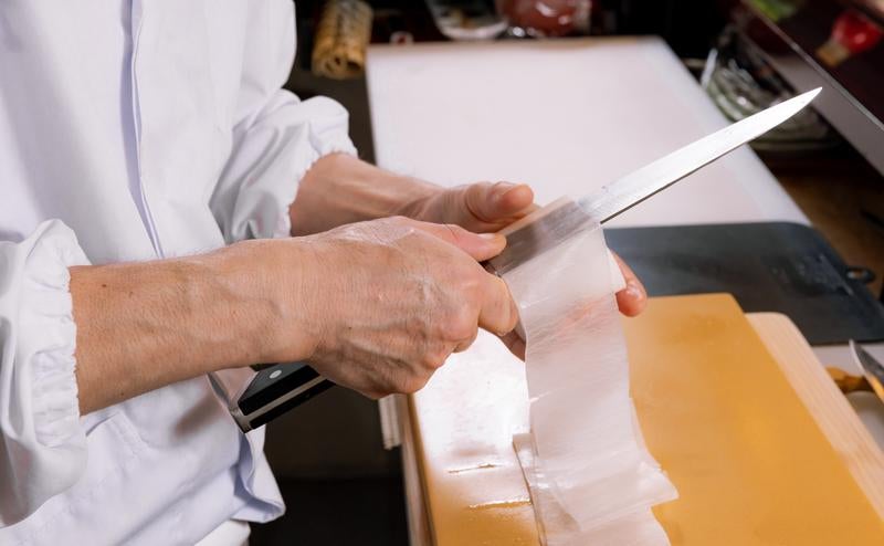 大根の桂剥きをする寿司職人の手元の写真