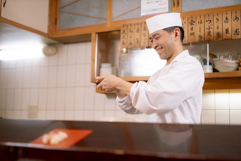 笑顔で寿司を握る寿司職人の写真