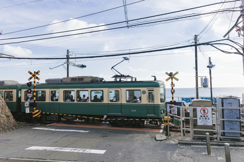 アニメのワンシーンで登場しそうな鎌倉高校前駅の踏切と江ノ電の写真