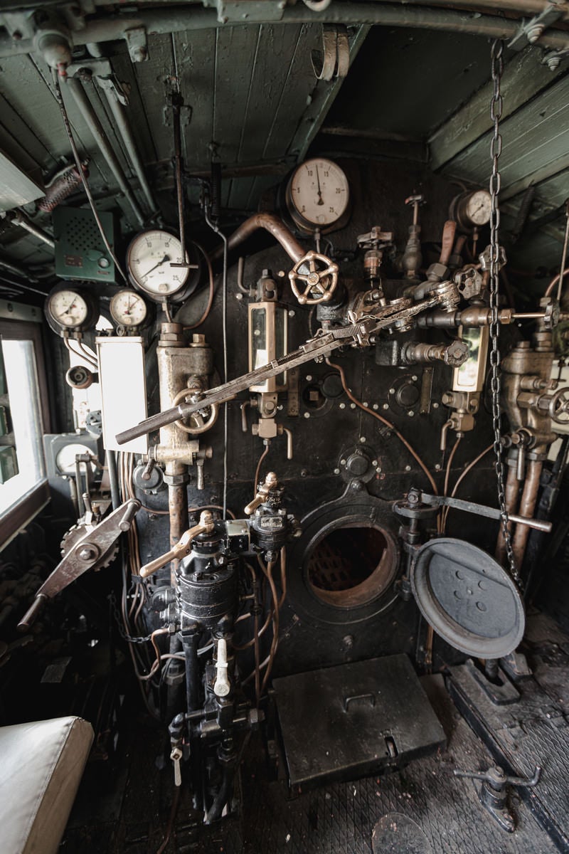 「計器類が並ぶ蒸気機関車の機関室内の様子」の写真