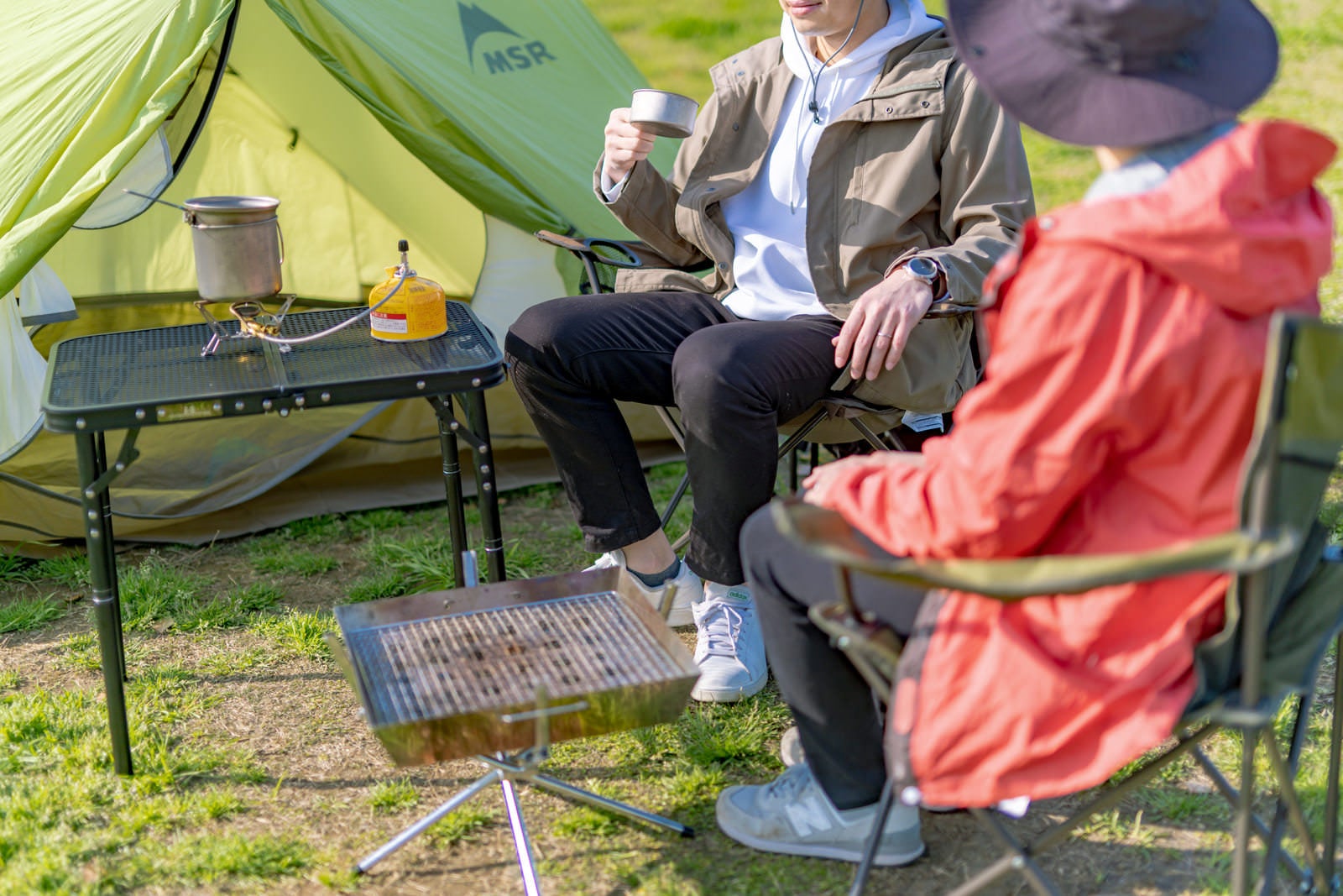 「キャンプ場でテントを張って団らんする二人」の写真