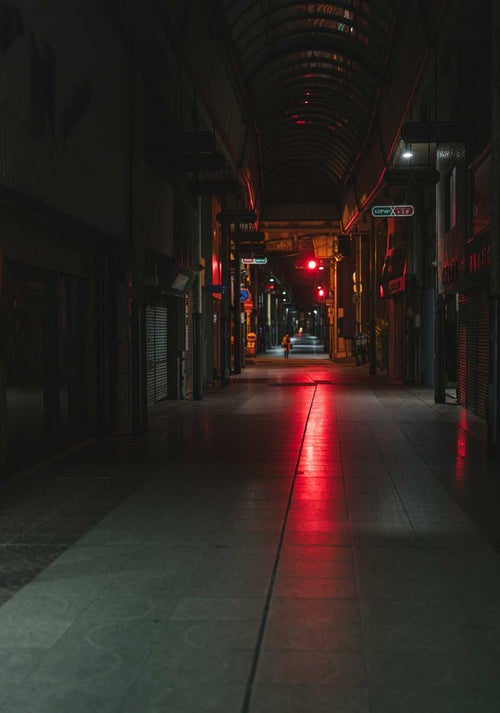 赤信号の光が伸びる深夜の直方市古町商店街の写真
