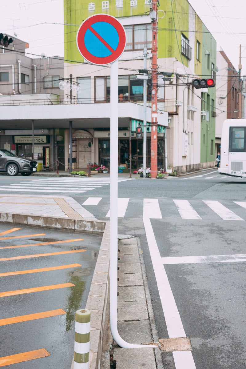 「道路上の関係で根元がＬ字に曲がった駐車禁止の標識」の写真