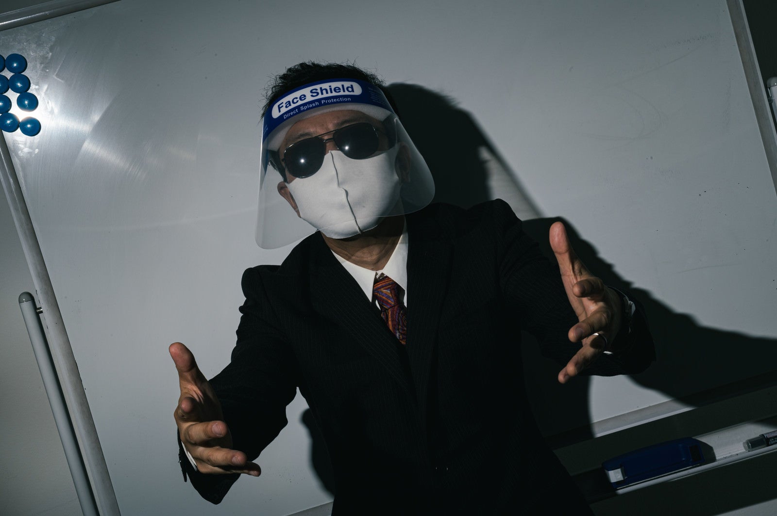 「フェイスシールドにマスクとサングラス姿でプレゼン」の写真［モデル：のせさん］