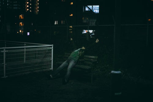 誰もいない夜の公園ガッツポーズからの伸びをする男性の写真