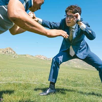 草原で対峙するスーツ着用のビジネスマンと挑戦者の写真