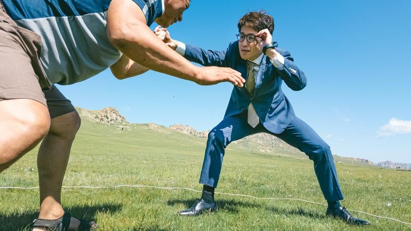 草原で対峙するスーツ着用のビジネスマンと挑戦者の写真