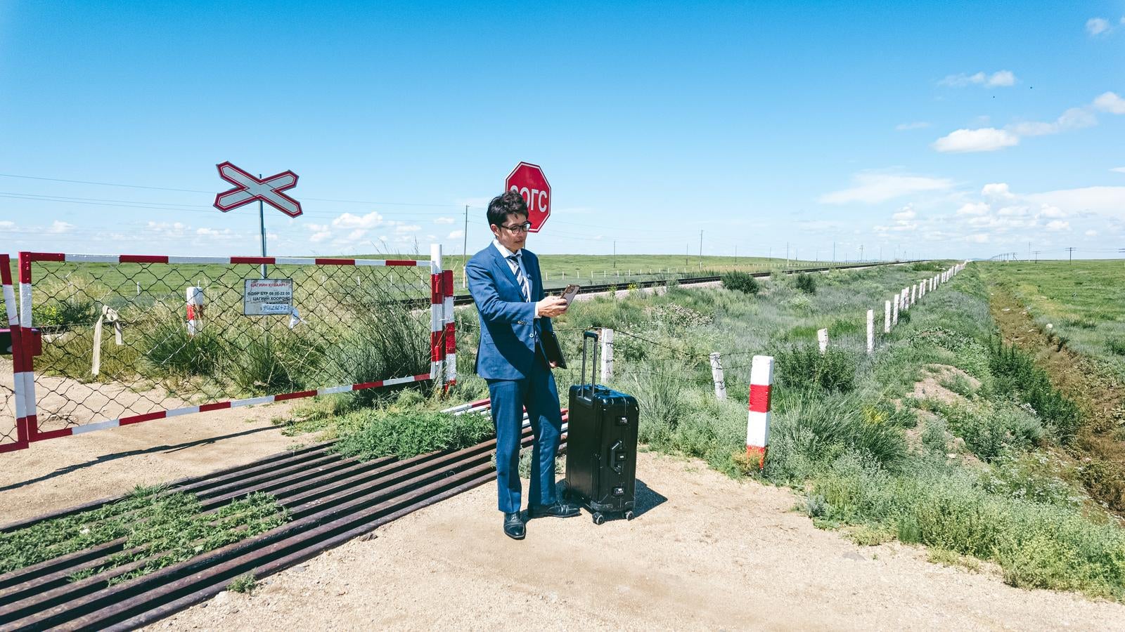 「モンゴルの草原と遠く続く線路に立ち止まる男性」の写真［モデル：野崎繁裕］