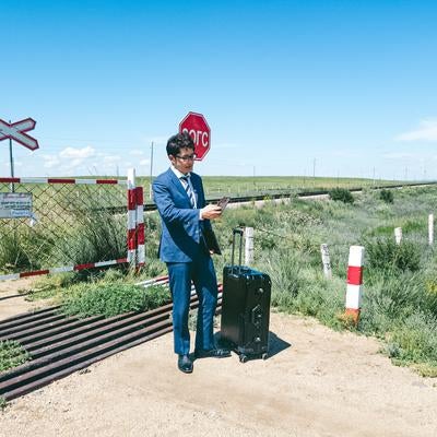 モンゴルの草原と遠く続く線路に立ち止まる男性の写真