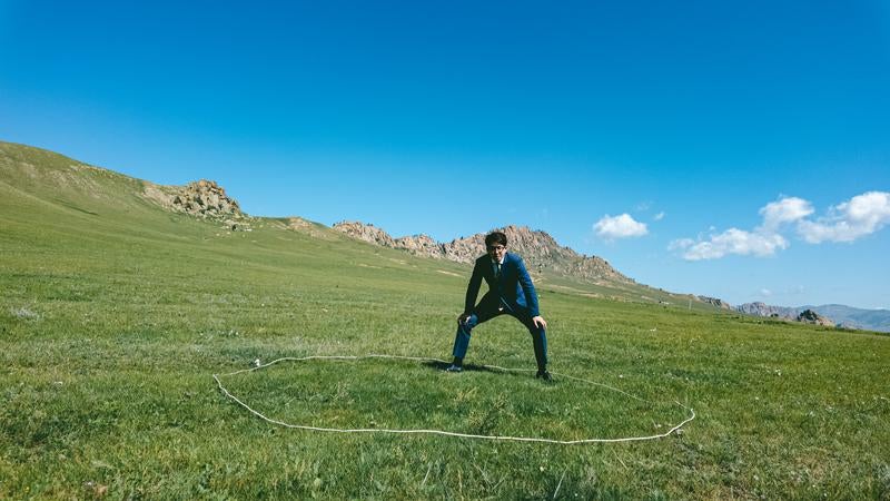 草原のしこを踏むスーツ姿の男性の写真