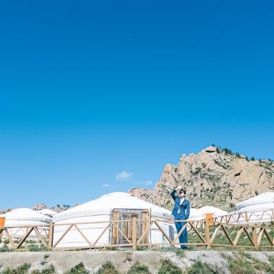 モンゴルの草原に並ぶゲルとスーツ姿の男性の写真