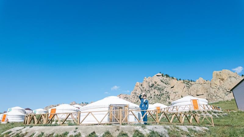 モンゴルの草原に並ぶゲルとスーツ姿の男性の写真