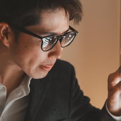 ブラインドの隙間から覗き込む捜査官風の様子の男性の撮影の写真