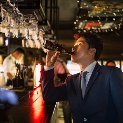 BARカウンターでビールを嗜む会社員の写真