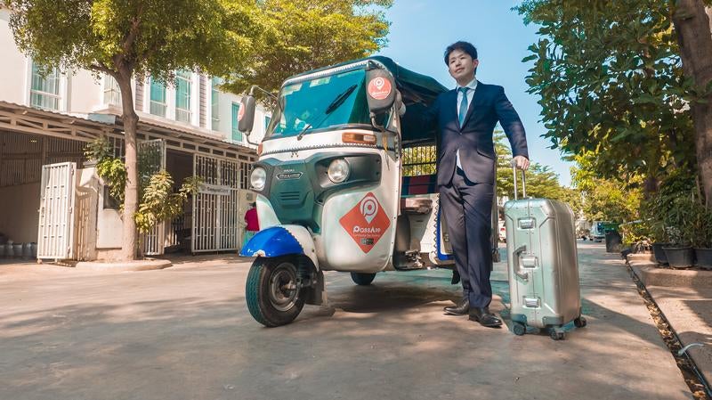 トゥクトゥクで出社するスーツ姿の男性の写真