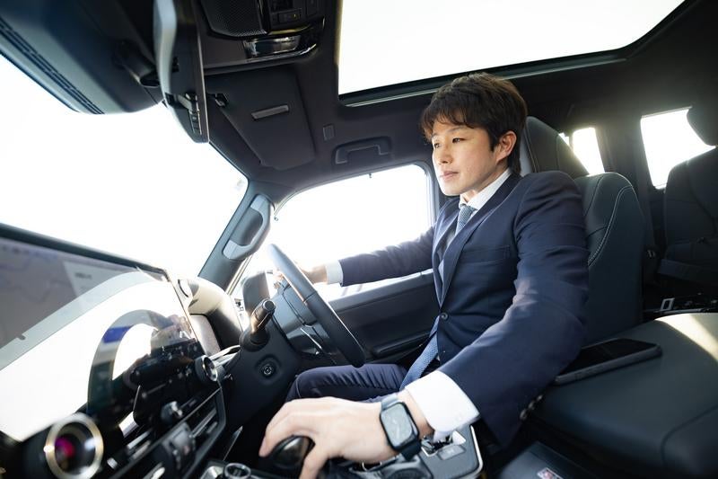 運転席でハンドルを握るスーツ姿のビジネスマン