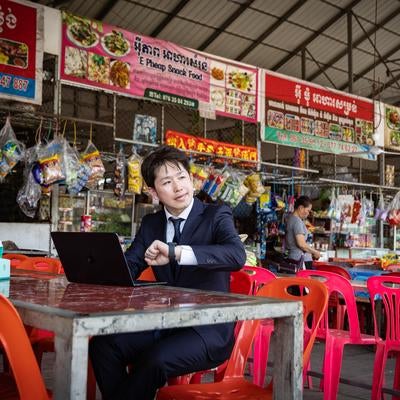 異国のフードコートで仕事に集中する男性ビジネスマンの写真