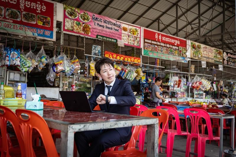 異国のフードコートで仕事に集中する男性ビジネスマンの写真