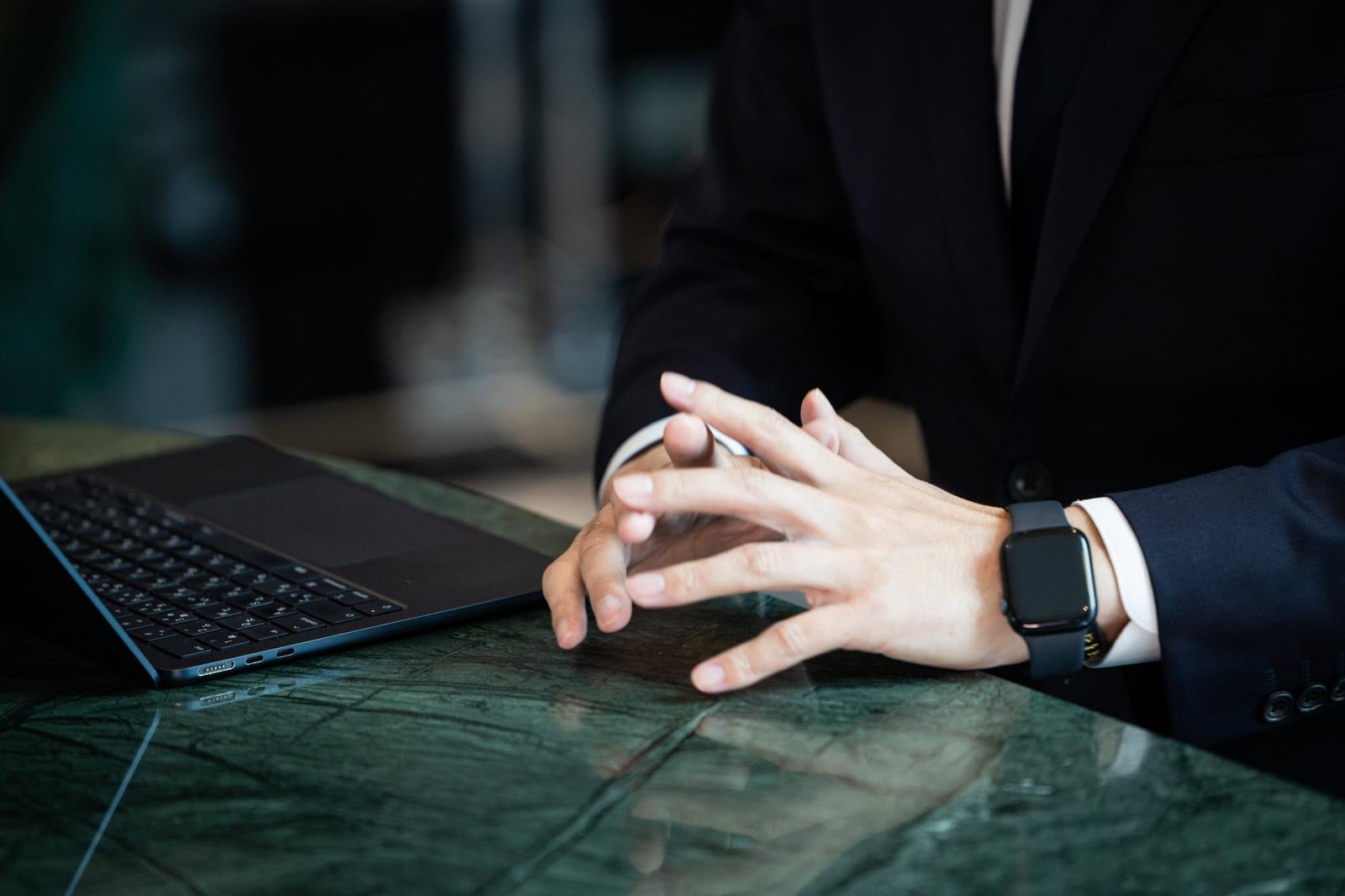 「デスクで手を組み考えるコンサルタント」の写真