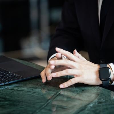 デスクで手を組み考えるビジネスマンの写真