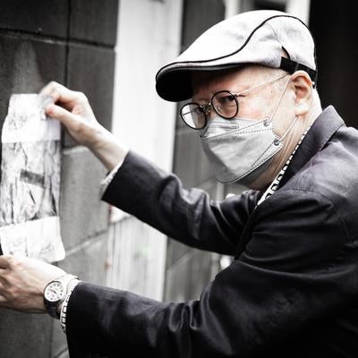 怪文書を壁に貼る高齢の男性の写真