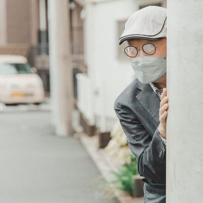 電柱に隠れて追跡する不審な男性の写真