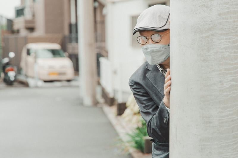 電柱に隠れて追跡する不審な男性の写真