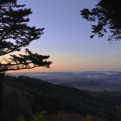 朝焼けに染まる空と山の中腹から見下ろす町並みの写真