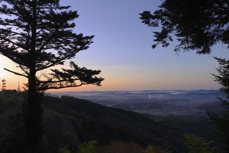 朝焼けに染まる空と山の中腹から見下ろす町並みの写真