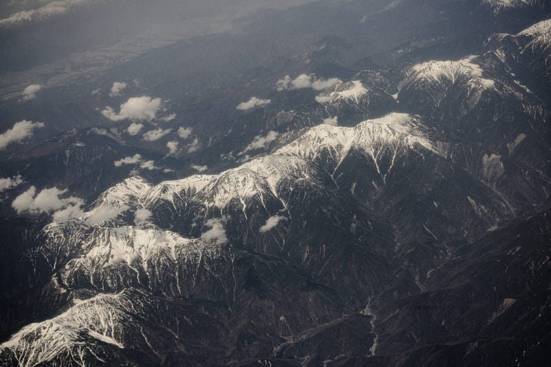 山頂付近に雪が残るアルプスの写真