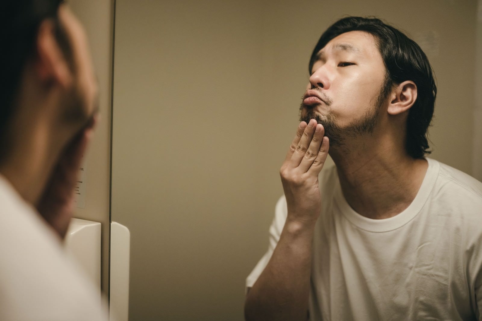 「洗面台の鏡で髭を整える男性」の写真［モデル：大川竜弥］