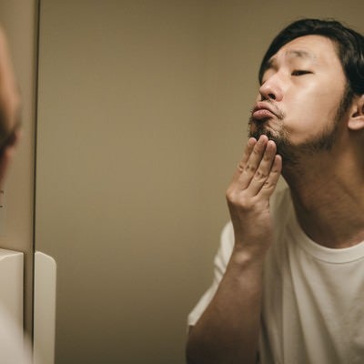 洗面台の鏡で髭を整える男性の写真