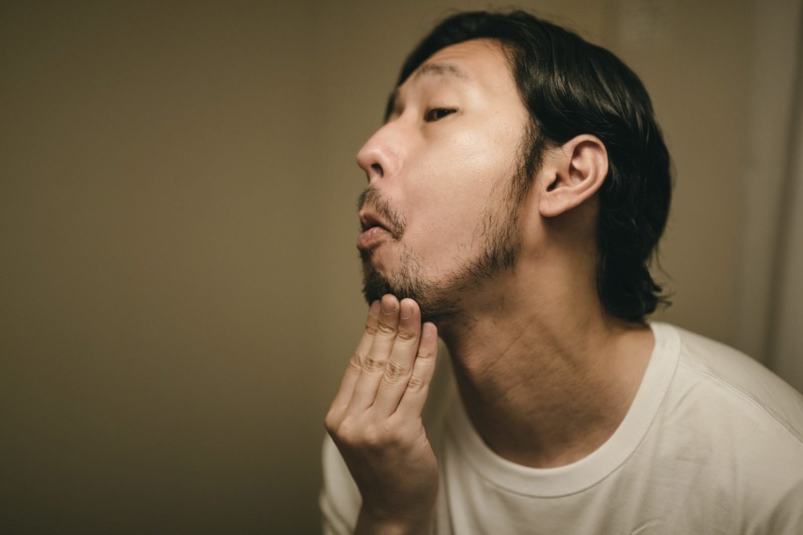 「髭の伸び具合を確認する男性」の写真［モデル：大川竜弥］