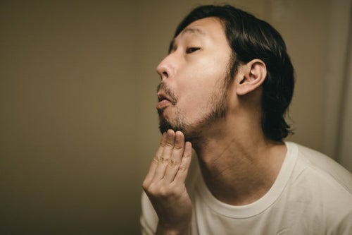 髭の伸び具合を確認する男性の写真